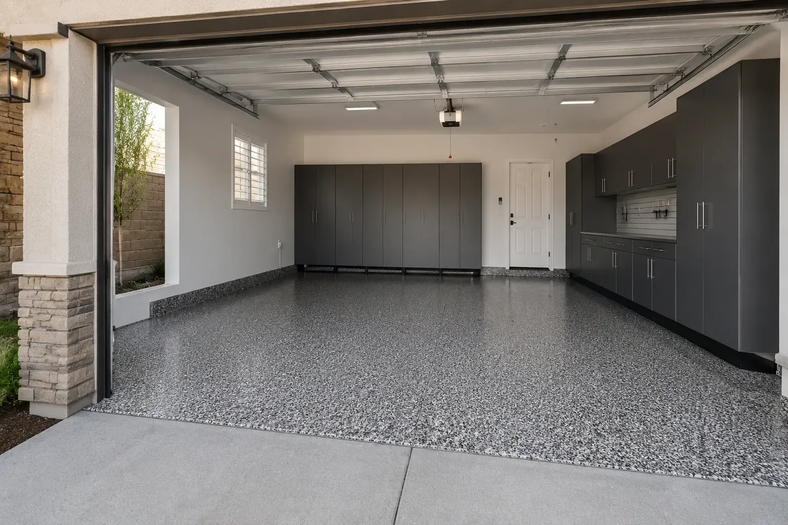 Example of a gray, white and black flake floor in a two-car garage with charcoal cabinets — Chino, CA service area