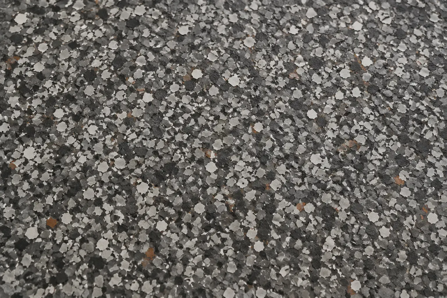 Close-up of a decorative flake floor: gray, white and black vinyl flakes with copper flecks.