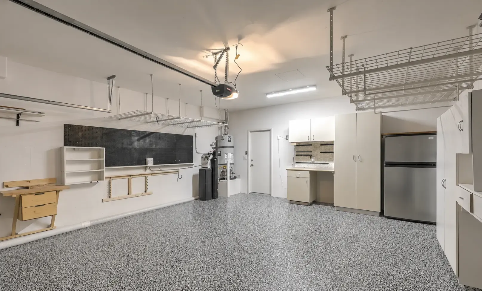 Example of a gray full-flake floor in an organized garage with overhead storage racks — Claremont, CA service area