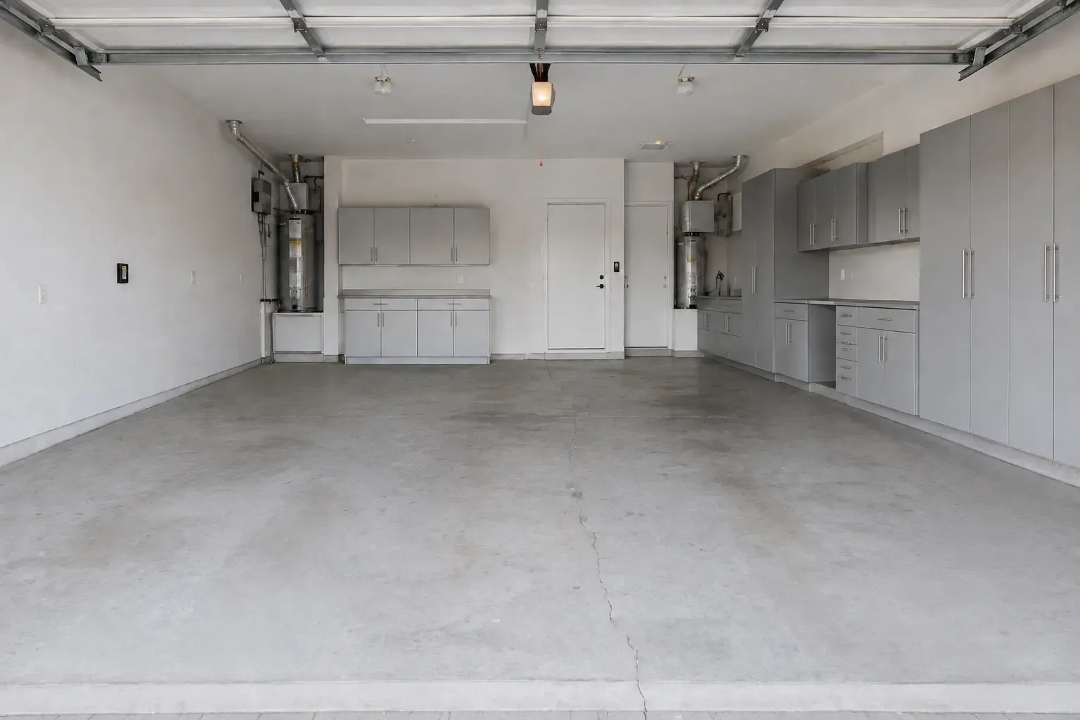 Wide Upland-style garage with a bare gray concrete slab and a long hairline crack, before coating.